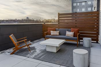 A wooden chair and a white table are on a patio.